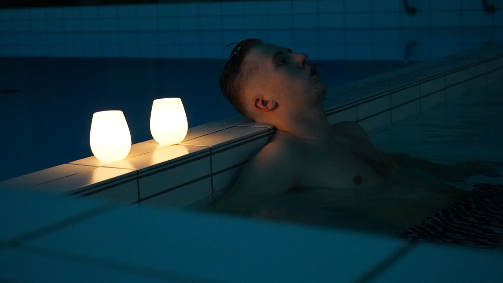 Man relaxing by candlelight in the swimming pool at Hedensted Centret