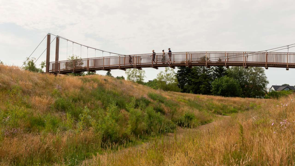 Tre personer går over hængebro i Bakkelunden i Horsens