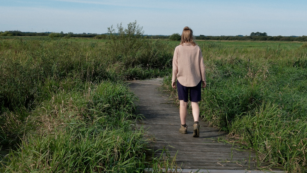 Kvinde går på boardwalk i Uldum Kær