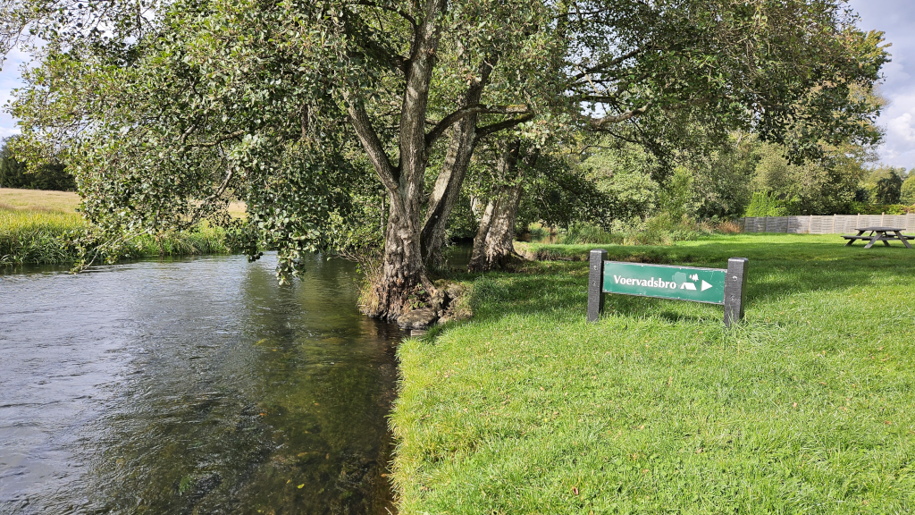 Et skilt til Voervadsbro Teltplads set fra Gudenåen