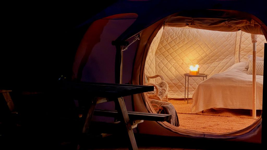 Glampingtelt set udefra om aftenen med kig ind