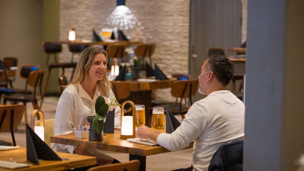 Restaurant Det Gode Selskab på Pejsegården, hvor et par sidder et bord i restauranten.