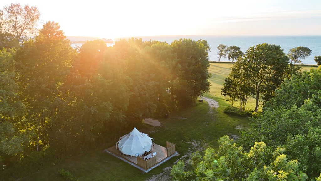 Campingpladsen Endelave set oppefra med fokus på glampingtelt og havudsigt