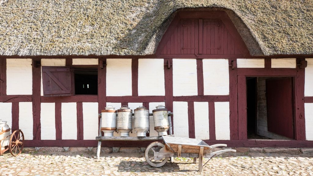 Glud Museum – a half-timbered farm building viewed from the outside, with traditional milk churns standing outside.