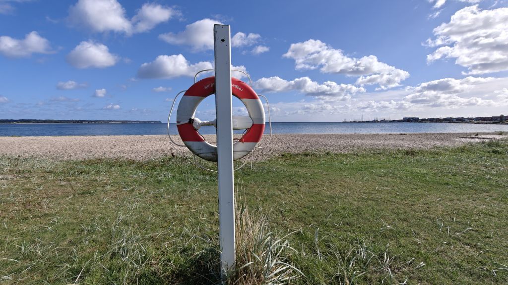 Lifebuoy, marram grass, sand and sea at Sandbjerg Vig near Juelsminde.