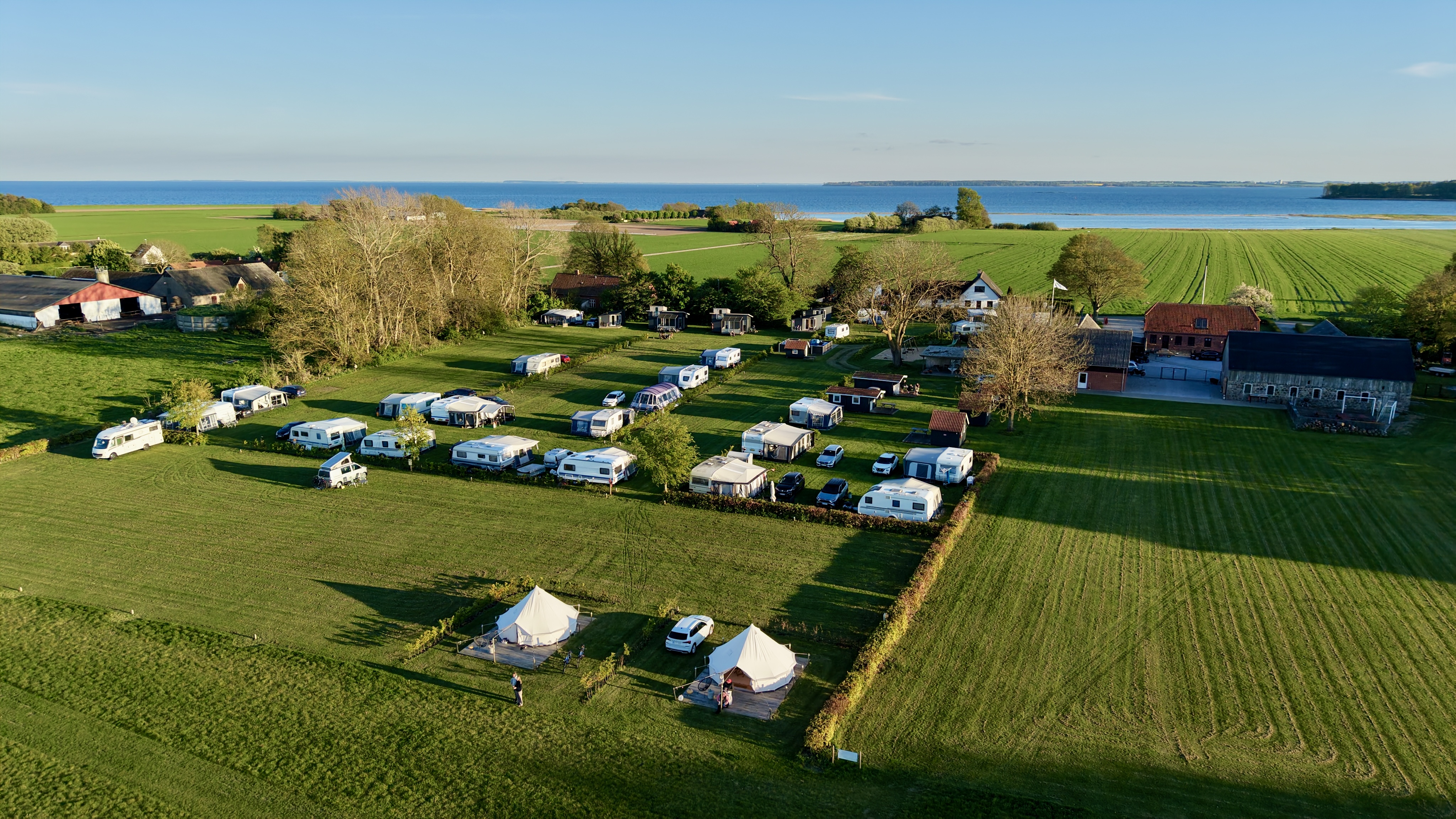 Dronefoto af Hjarnø Camping med Horsens Fjord i baggrunden