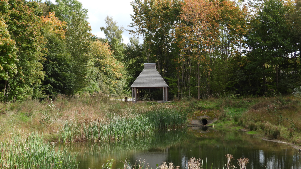 En træbygning ved en sø i Natur Østbirk