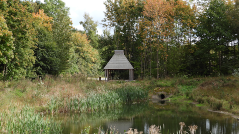 En træbygning ved en sø i Natur Østbirk