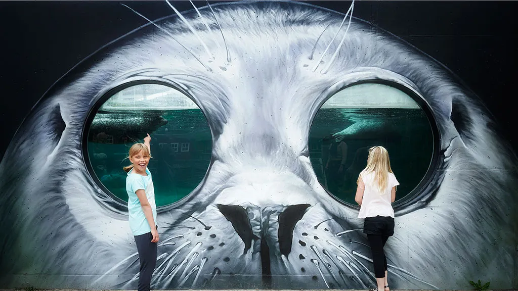 Children in front of a mural of a seal