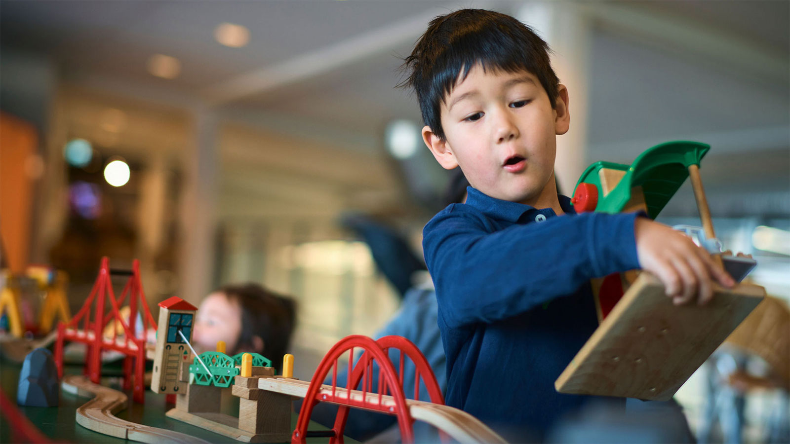 Boy playing with a wooden railway set at the Danish Railway Museum