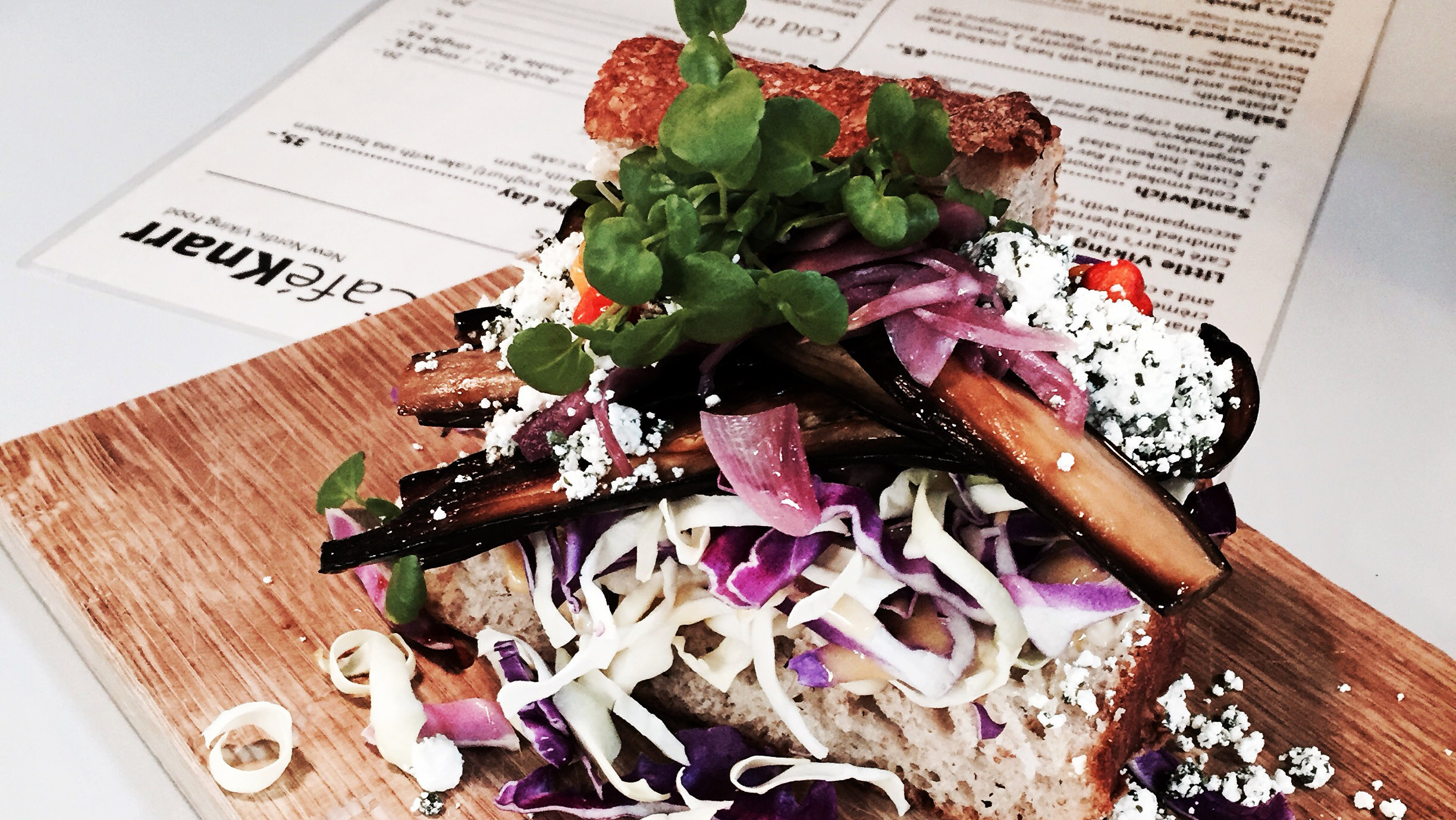 A plated dish with greens on a wooden board at Café Knarr
