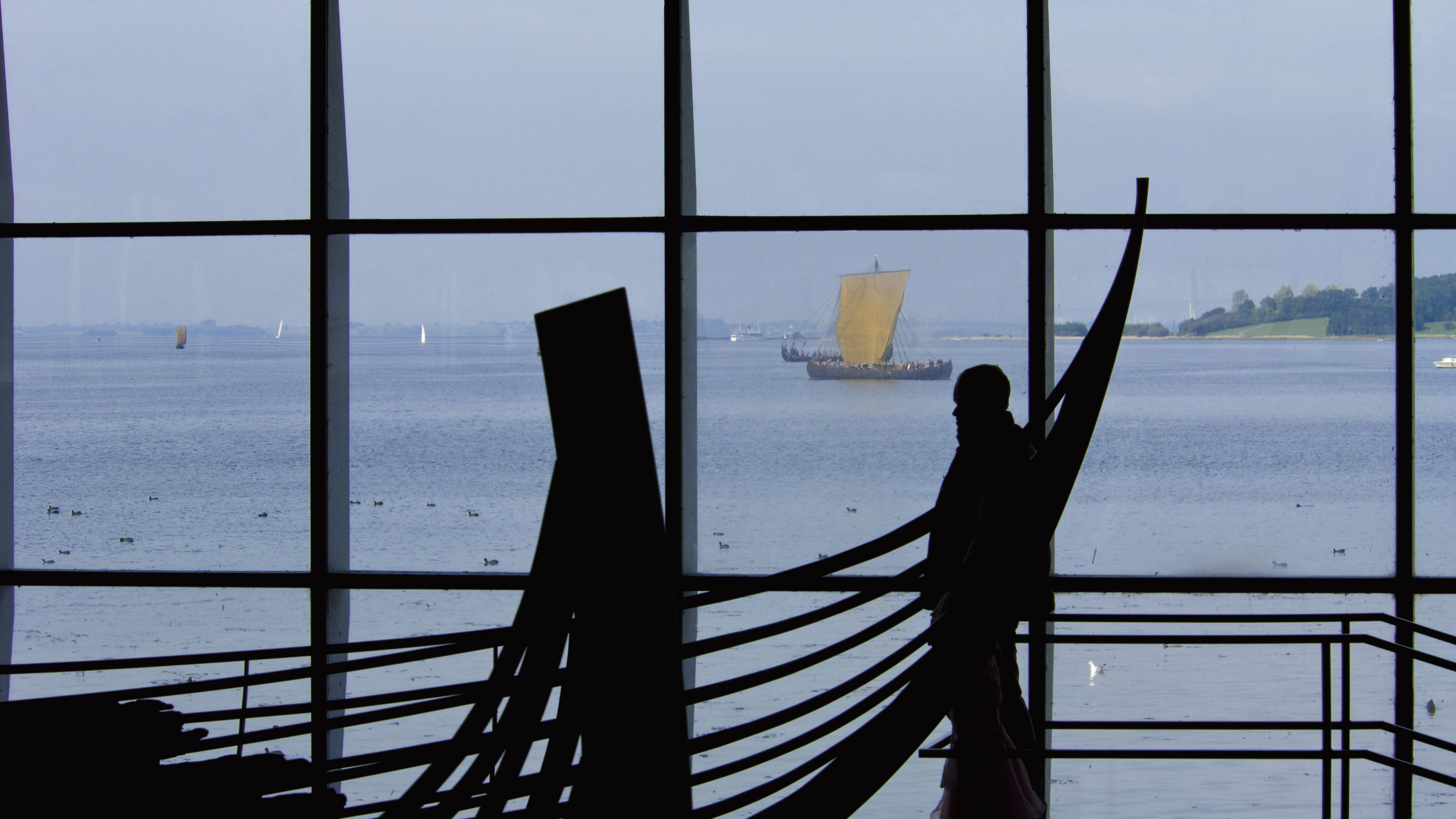An original Viking ship in the museum hall with the fjord beyond the windows