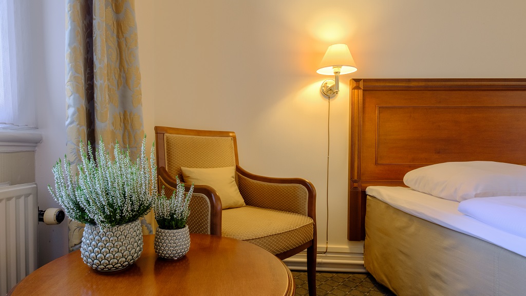 Klassisches Hotelzimmer mit Holzmöbeln, Sessel und Bett im Four Points Flex by Sheraton Roskilde.