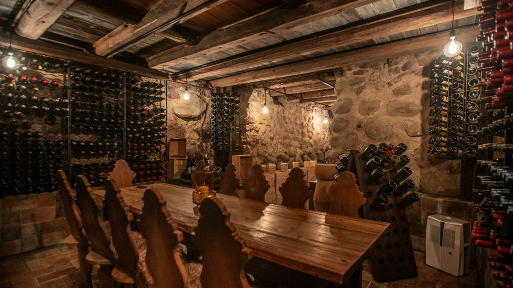 Wine cellar with bottles, stone walls and a wooden table at Skoemagerkroen