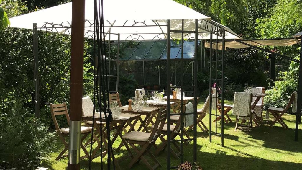 Garden chairs and a table under a parasol at Chefs Cottage and Garden Café
