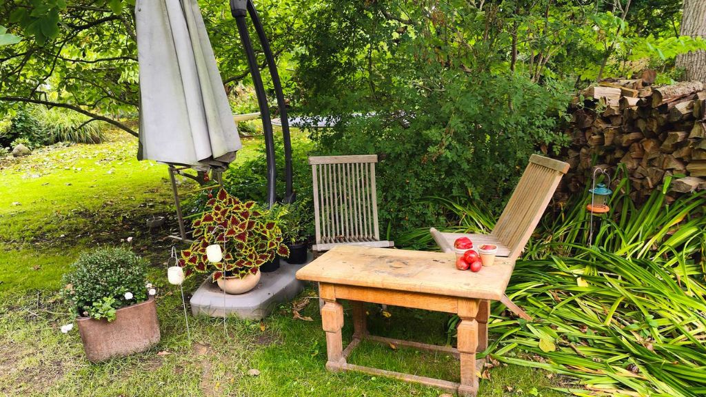 Stuhl und Tisch im üppigen Garten bei Chefs Cottage and Garden Café