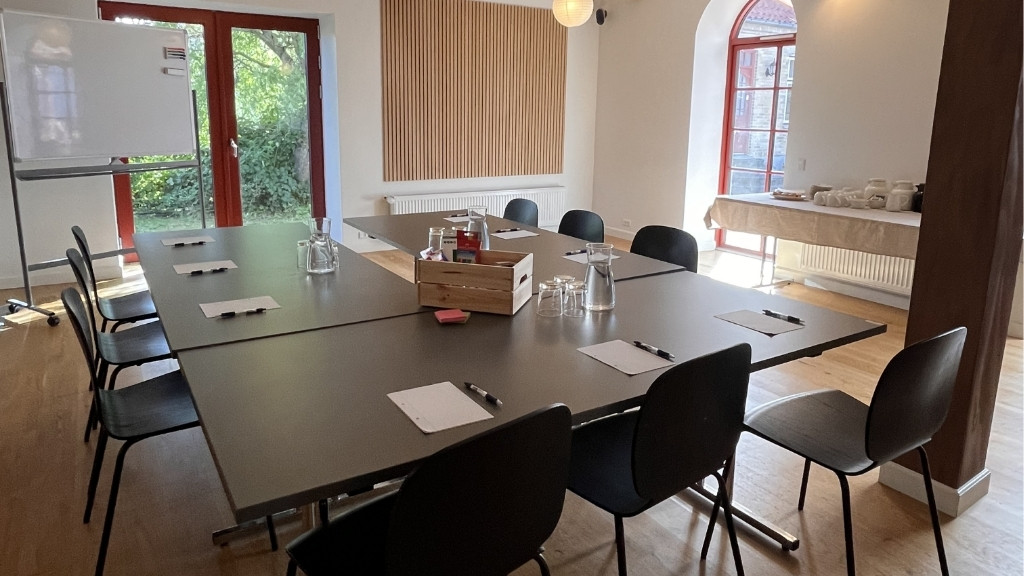 Lyst mødelokale på Nordgården med borde, stole og forplejning.