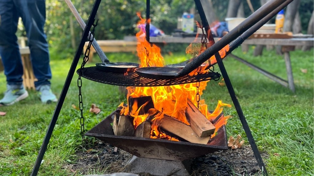 Udendørs bålsted på Nordgården med ild og grillrist.