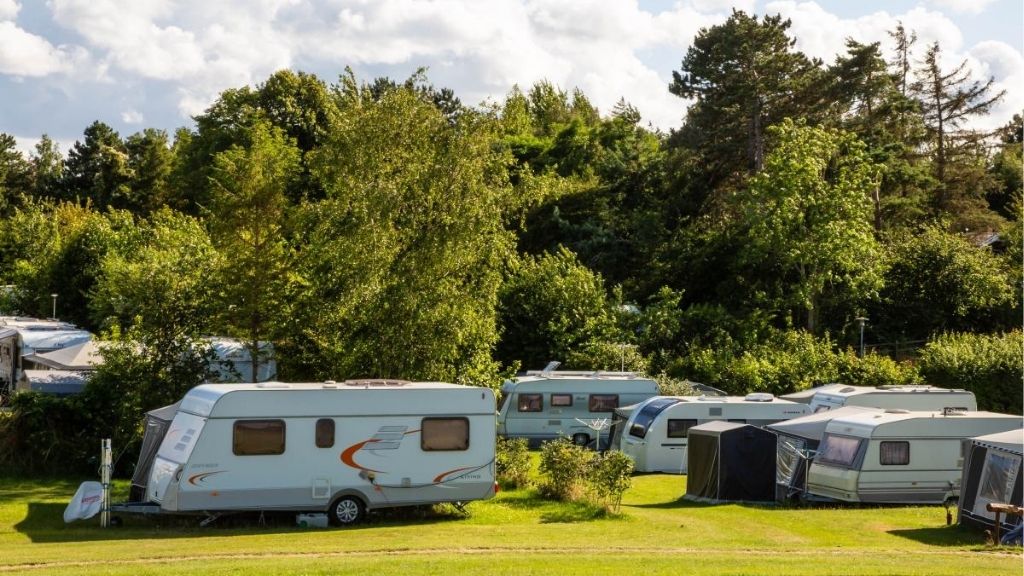 Caravans on grassy area surrounded by nature at Kulhuse Camping.