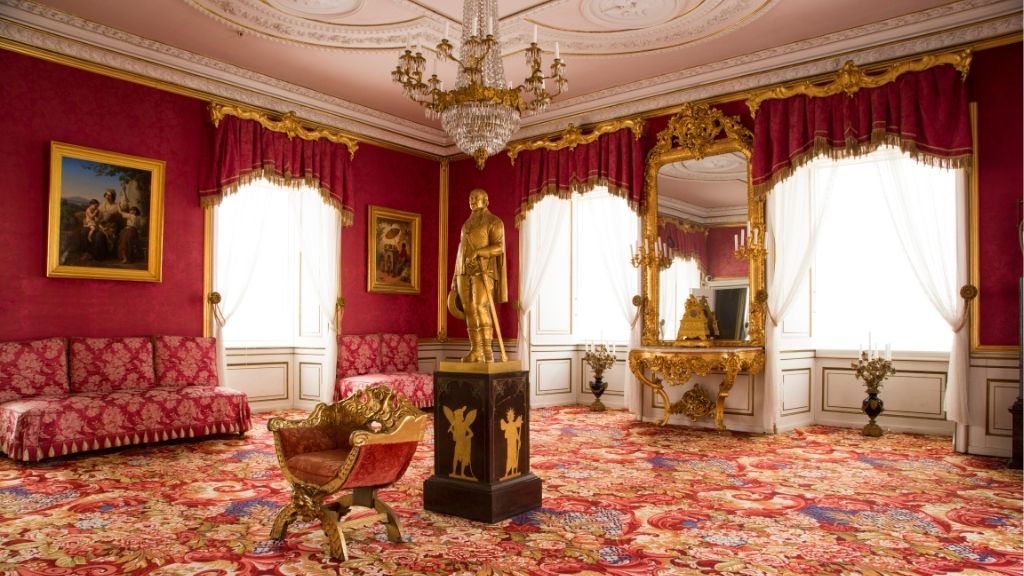 Historic room at Jægerspris Castle with red textiles and a chandelier