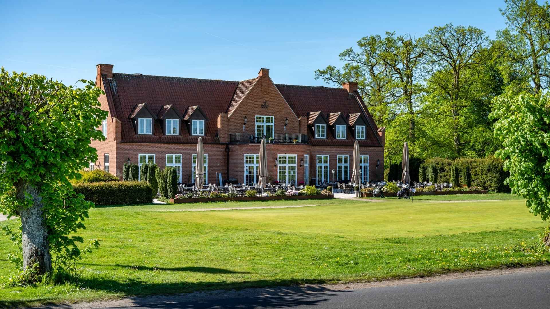 Clubhouse at Ledreborg Palace Golf Club with terrace and green surroundings.