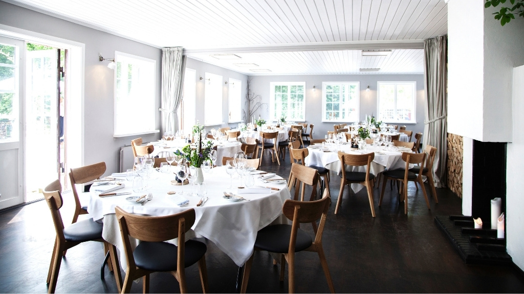 Selskabslokale hos Restaurant Herthadalen med runde borde og hvid dug.