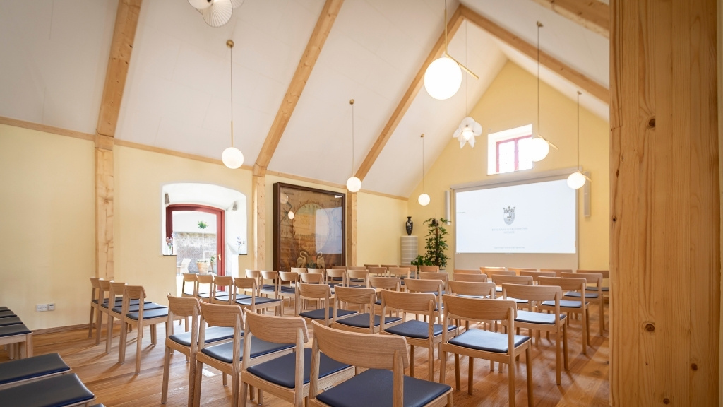 Konferencesal i Fårestalden på Ryegaard Gods med rækker af stole og projektor.