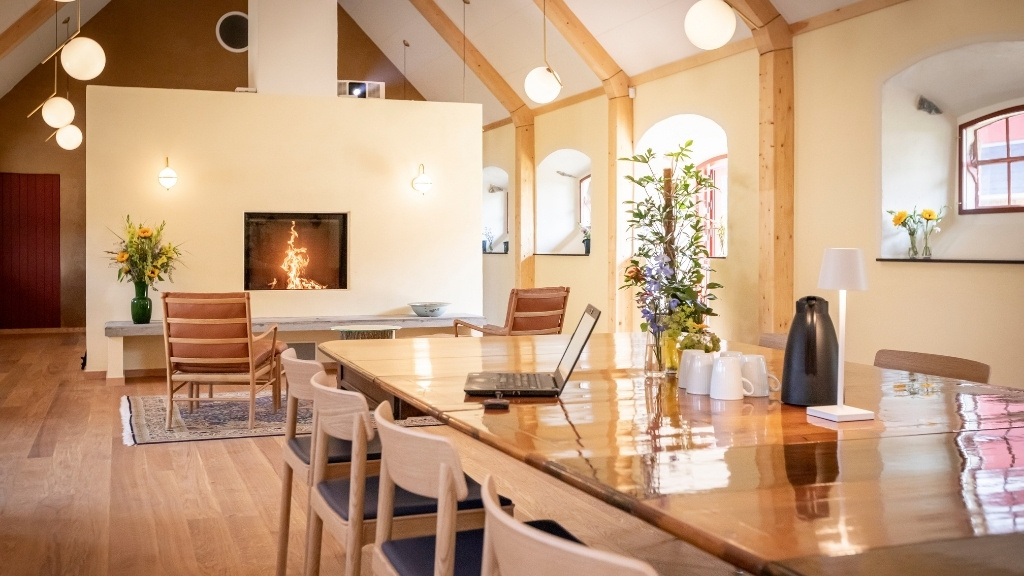 Opholdsrum i Fårestalden på Ryegaard Gods med langbord og pejs.