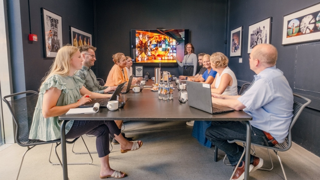 Møde på RAGNAROCK med præsentation og deltagere omkring bord.