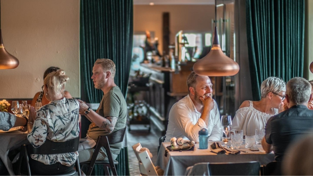 Gæster i restauranten på Skovmagerkroen med hyggelig stemning og dækkede borde.