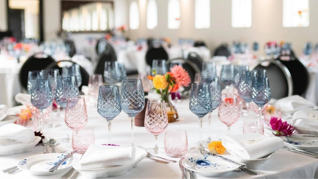 Selskabslokale på Skovmagerkroen med opdækkede borde, glas og blomster.