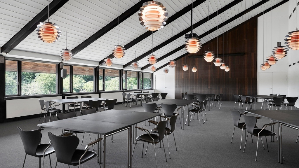 Konferencelokale på Metalskolen med borde, stole og moderne belysning.