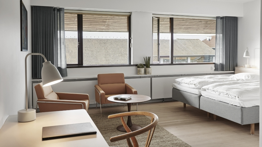 Moderne hotelværelse på Metalskolen med senge, skrivebord og siddeplads.