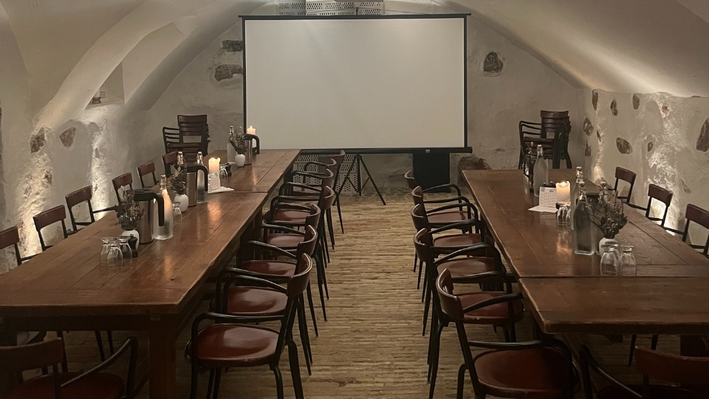 Mødelokale hos Restaurant Bryggergården med langborde og projektorlærred.
