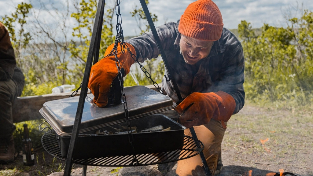 Madlavning over bål ved Bjælkehytten med gryde og ild.