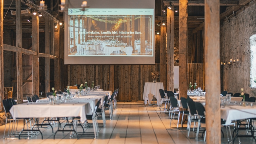 Conference hall at Sonnerupgaard Gods in a rustic barn with set tables.
