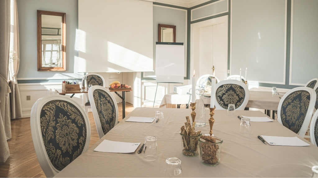 Classic meeting room at Sonnerupgaard Gods with round tables and elegant chairs.
