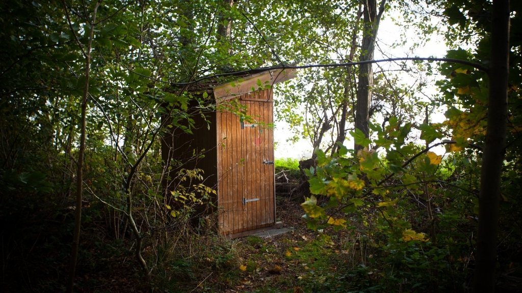 Holztoilette auf dem Wikingerlagerplatz, umgeben von Wald.