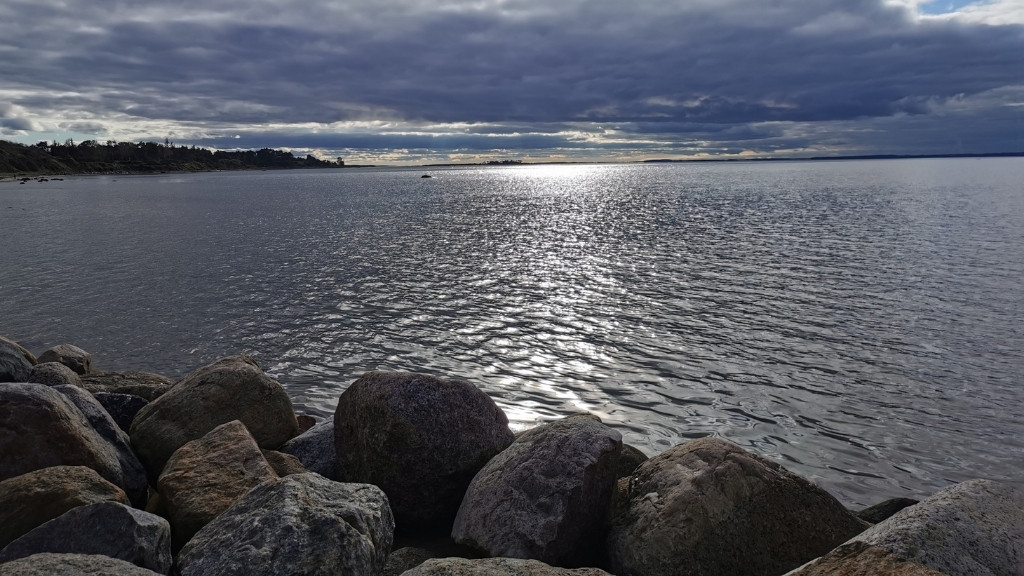 Fjordudsigt ved DCU Camping Kulhuse med stenstrand, vand og dramatisk himmel.
