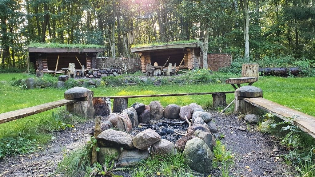 Bålplads med træbænke og shelters ved Friluftsladen i skoven.