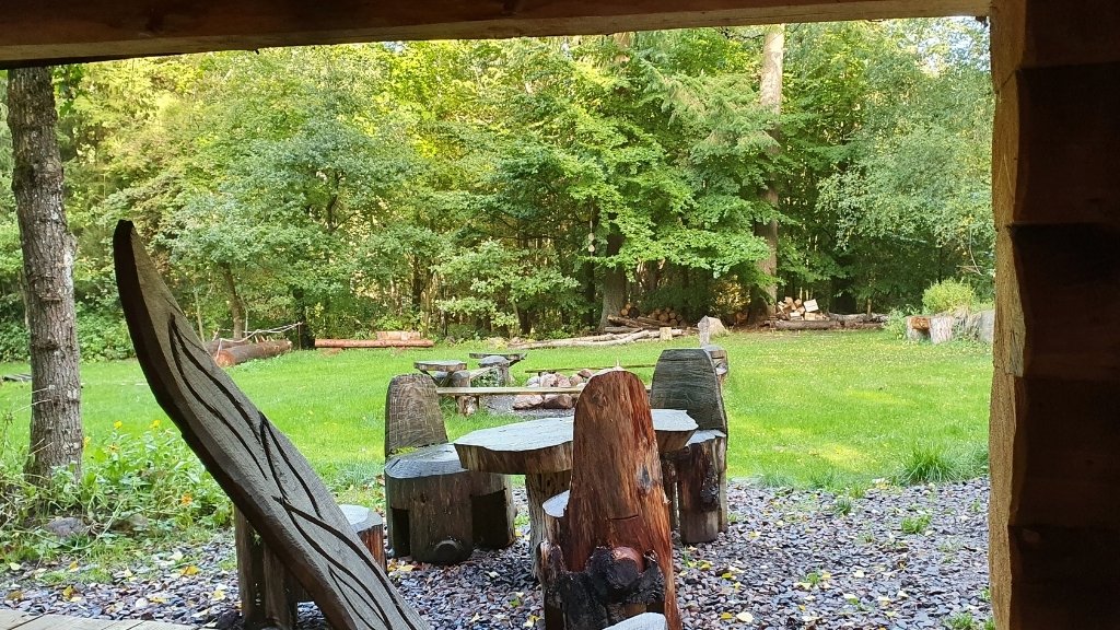 Udsigt fra shelter mod bålplads og træborde ved Friluftsladen.