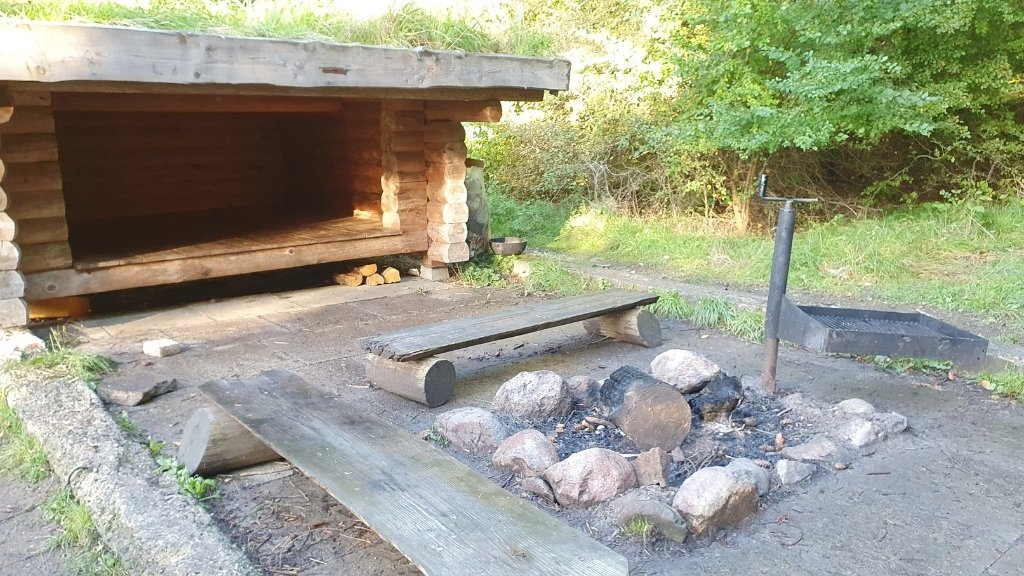 Campfire area with grill and shelter at Lerbjerg-Shelters in the forest.