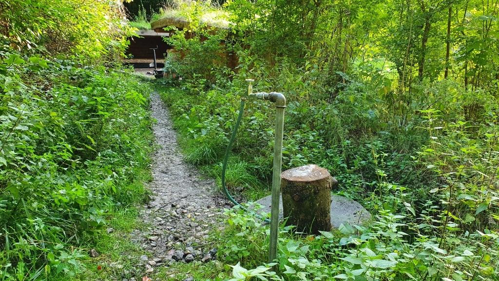 Path and water tap at Lerbjerg-Shelters surrounded by green nature.