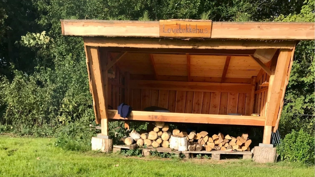 Shelter ved Løvebakkehus placeret i åbent grønt område.