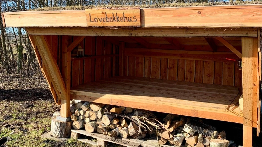 Træshelter ved Løvebakkehus placeret i skovkanten.
