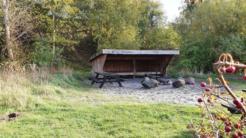Shelter Bifrost im Sillebro Ådal umgeben von grüner Natur.