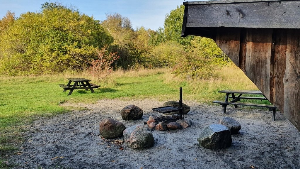 Feuerstelle bei Shelter Bifrost im Sillebro Ådal mit Grill und Sitzmöglichkeiten.