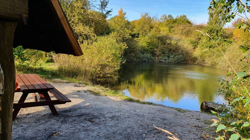Shelterbereich im Sillebro Ådal mit Picknicktisch und Blick auf den See.