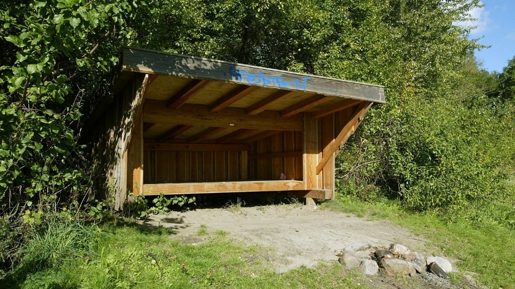 Holzunterstand bei Skuldelev Strand mit Feuerstelle davor.