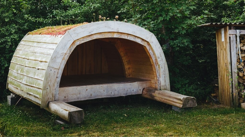 Holzunterstand auf dem Solbakken Naturistcamping, umgeben von grüner Natur.